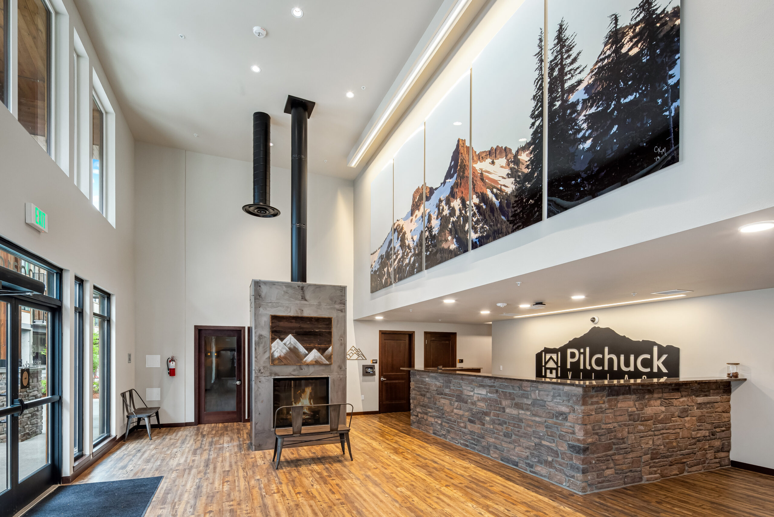 Luxury Apartments Near Downtown Arlington WA - Pilchuck Village - Apartment Lobby with a Wall Decor, Wood Flooring, & Fireplace Seating